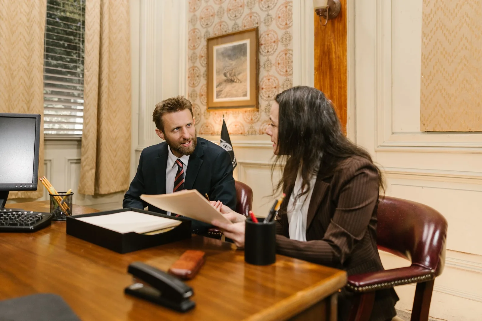 A lawyer and a client reading through a document across a desk