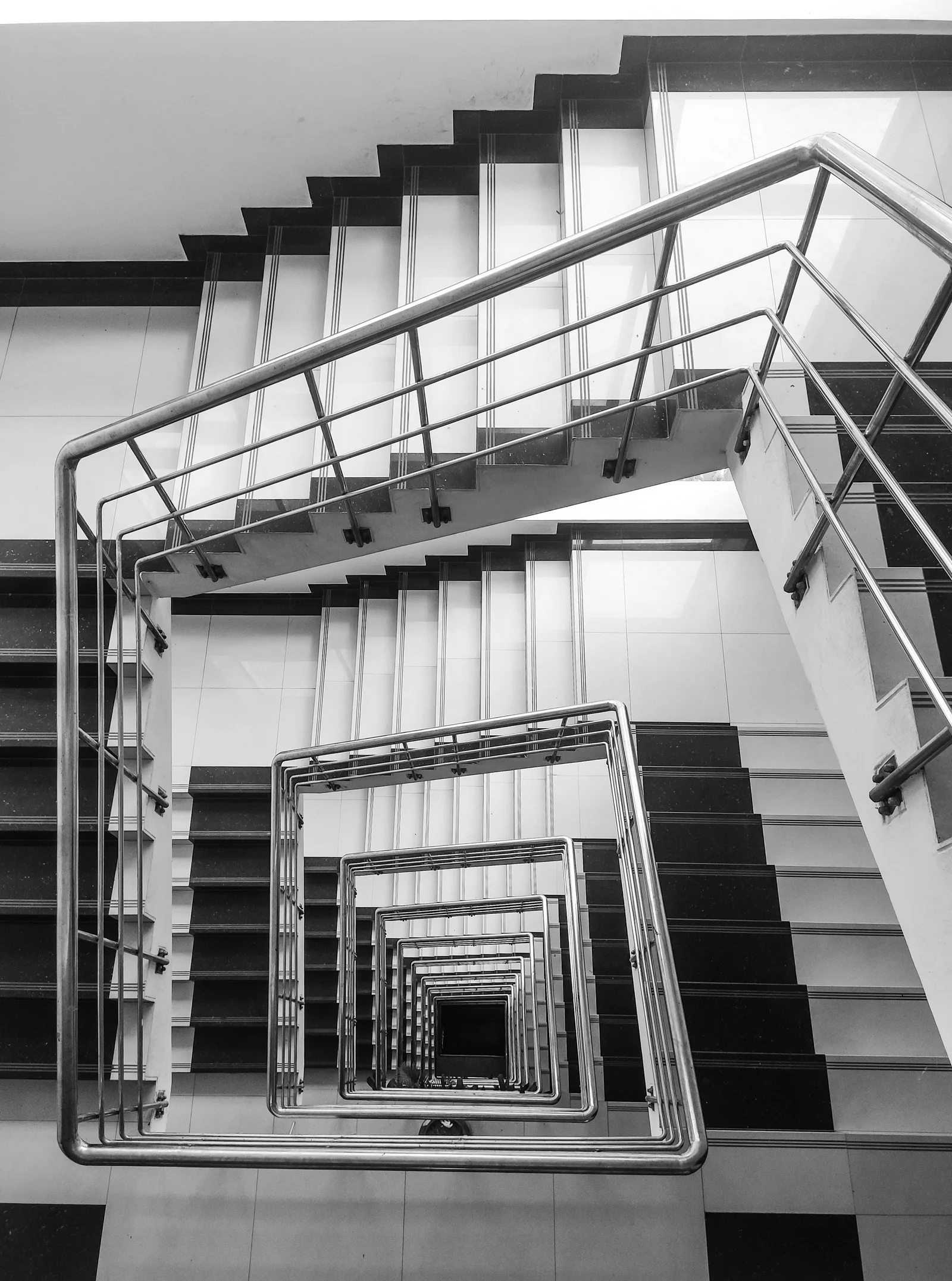 A square stairwell seen from below, its flights turning into the distance